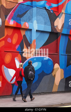 Couple walking passé street art graffiti sur Nelson Street, Bristol Banque D'Images