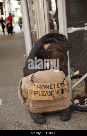 Jeune femme sans-abri tend la main avec un signe sur le trottoir à Midtown Manhattan. Banque D'Images