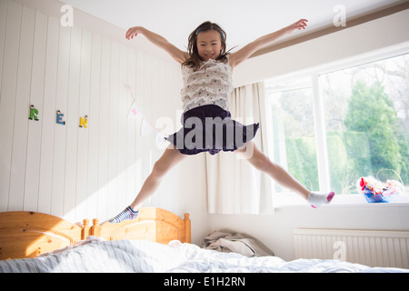 Young Girl jumping mid air on bed Banque D'Images