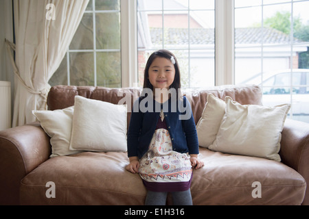 Portrait of young girl sitting on sofa Banque D'Images