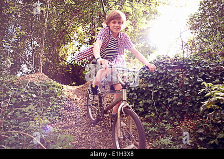 Vélo garçon à travers la forêt Banque D'Images