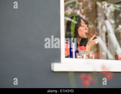 Femme mature à la fenêtre de la chambre d'alimentation dégustation spatule Banque D'Images