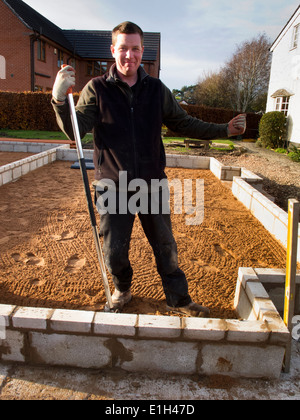 L bâtiment maison, l'homme sable aveuglantes sur sol compacté, base en attente de preuve humide membrane pour plancher Banque D'Images