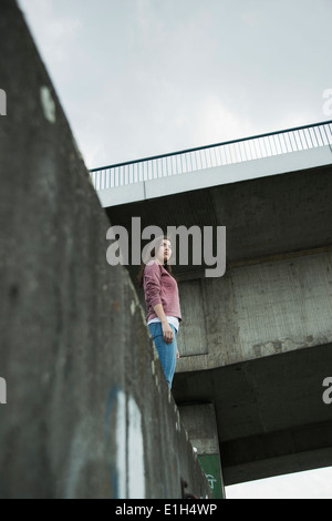 Young woman standing on wall, low angle Banque D'Images