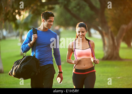 L'homme et la femme portant des vêtements de sports walking through park Banque D'Images