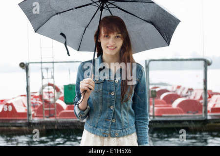 Portrait de jeune femme par le lac avec parapluie Banque D'Images