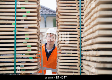 Portrait de jeune homme travailleur entre les piles de palettes en bois yard Banque D'Images