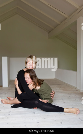 Mère et fille de douze ans hugging on floor
