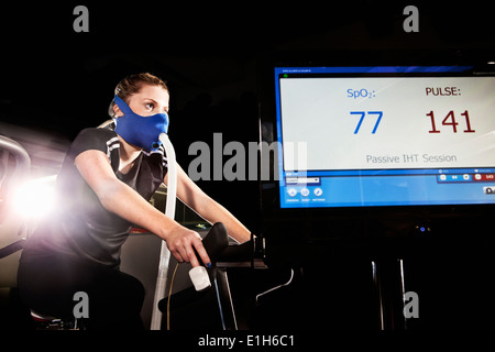 Jeune femme au masque de visage sur l'exercice de sport en altitude cycle center Banque D'Images