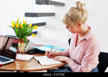 Young woman sitting at table écrit Banque D'Images