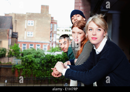 Quatre jeunes adultes, debout sur un balcon dans Londres, Royaume-Uni Banque D'Images