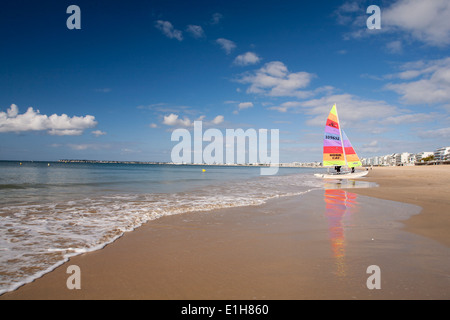 Yacht avec voile de couleur vive sur la plage Banque D'Images