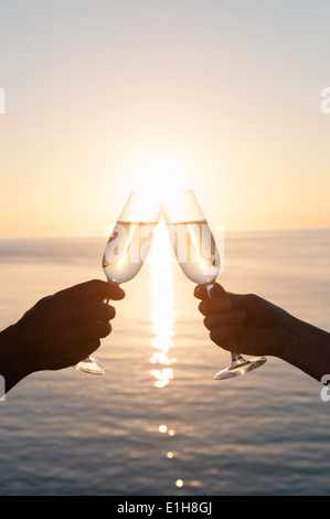 Couple toasting contre coucher du soleil Banque D'Images