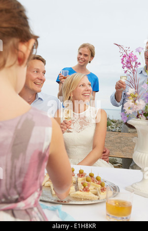 Couple faire un toast avec un groupe d'amis à la réception de mariage Banque D'Images