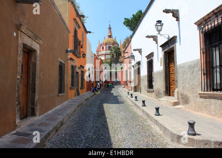 Regardant vers le bas de la rue pavée bordée de maisons en allant vers l'église de la Parroquia de San Miguel de Allende, Guanajuato, Mexique Banque D'Images