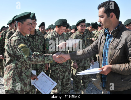 Une armée nationale afghane (ANA) soldat, à gauche, reçoit son certificat de fin de cours d'alphabétisation à une cérémonie de remise des diplômes Mars Banque D'Images