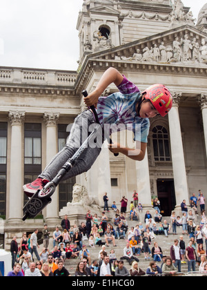 Un scooter rider effectue une cascade aérienne en face de la Portsmouth Guildhall au cours de la rue de Portsmouth en 2014 Banque D'Images