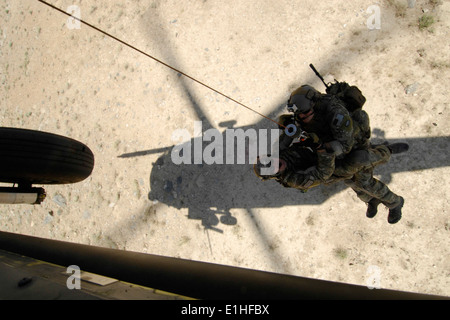 Un cavalier de sauveteurs-parachutistes et un sauvetage de combat militaire du 83e Escadron de sauvetage expéditionnaire sont hissés dans un U.S. Air Force H Banque D'Images