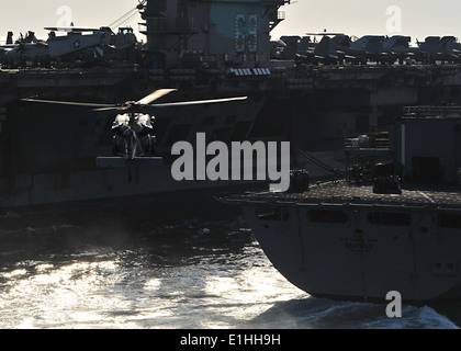 Un U.S. Navy hélicoptère MH-60S Knighthawk se prépare à aller chercher la cargaison de l'USNS Navire de soutien de combat rapide (T-AOE 6) duri Banque D'Images