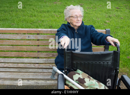 Quatre-vingt-dix ans, femme assise sur banc de parc en automne en Angleterre. UK Banque D'Images