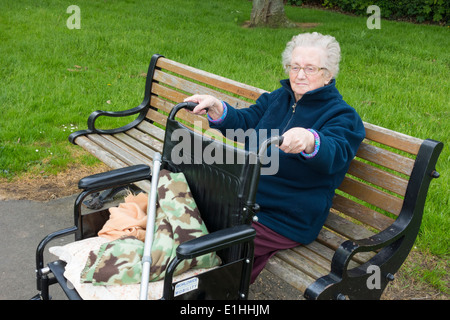 Quatre-vingt-dix ans, femme assise sur banc de parc en automne en Angleterre. UK Banque D'Images