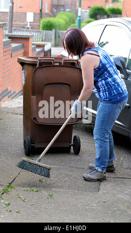 Une femme d'âge moyen des déchets de jardin sur une entrée de l'Angleterre UK Banque D'Images