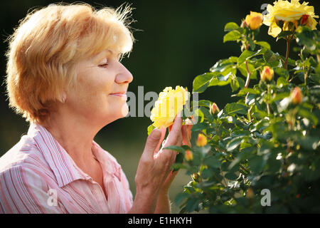 L'expression. Modèle femme senior avec jardin Roses. Printemps Banque D'Images