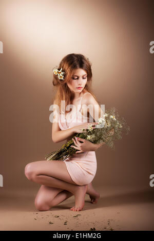 Barefoot Auburn sentimentale Woman Relaxing with Wildflowers Banque D'Images