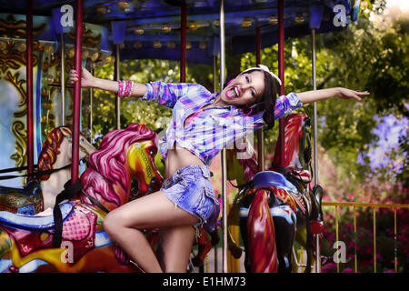 Fête foraine. Cheerful Woman in Amusement Park sur Carrousel. Jouissance Banque D'Images