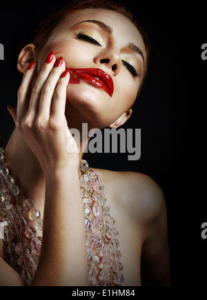 Femme avec des taches de rouge à lèvres rouge sur fond noir Banque D'Images