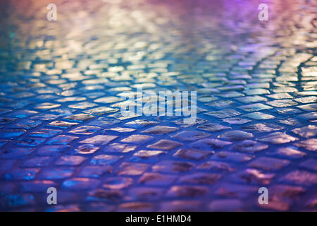 Cobble chaussée de pierre - Réflexion dans la nuit urbaine. Trottoir bleu humide Banque D'Images