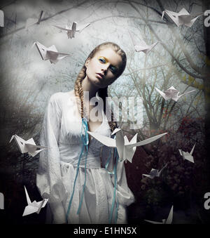 L'imagination. Blonde romantique avec l'Origami planant dans les oiseaux de la forêt Spooky. Magic Banque D'Images