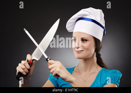Portrait d'une femme chef de l'affûtage couteau sur fond gris Banque D'Images