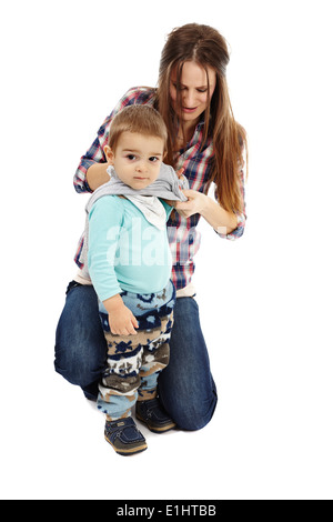 Young caucasian mother s'habillant avec son petit garçon, isolé sur fond blanc Banque D'Images