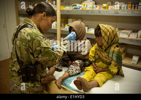 Une fille afghane, droite, observe un Marine américain, à gauche, donne sa sœur antitussif dans la province de Herat, Afghanistan, 10 févr. Banque D'Images