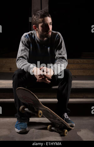 Skater sitting on steps dans le skate park Banque D'Images