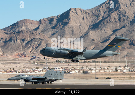 Un U.S. Air Force C-17 Globemaster III atterrit à Nellis Air Force Base, Nevada, comme trois F-15C Eagles affecté à la 48e Banque D'Images