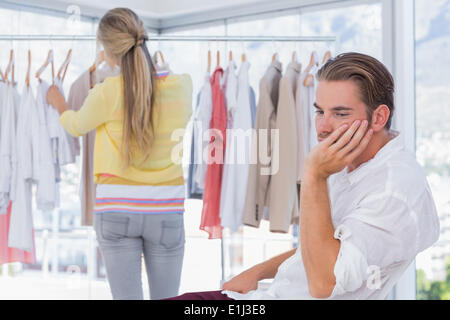 Bored man alors que sa petite amie est shopping Banque D'Images