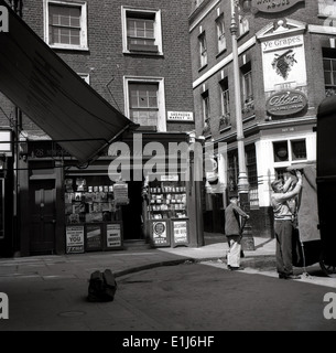 Années 1950, image historique de cette époque montrant un magasin d'angle, un marchand de journaux et un vieux (1882) pub victorien, Ye Grapes à Mayfair, au marché Shepherd, Londres, W1, une charmante place au large qui mènent un certain nombre de petites rues pavées, l'Angleterre. Souvent appelé « le secret le mieux gardé de Londres ». Banque D'Images