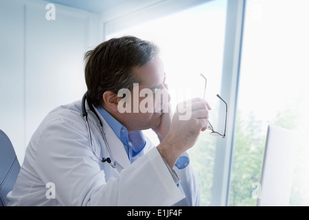 Doctor holding eyeglasses, se frottant les yeux Banque D'Images