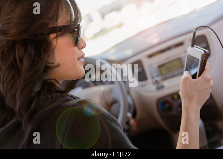 Jeune femme de la lecture de texte sur son portable dans... Banque D'Images