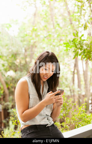 Young woman using smart phone on porch Banque D'Images