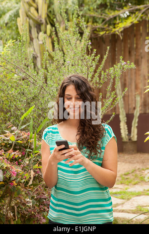 Girl in garden using smartphone Banque D'Images