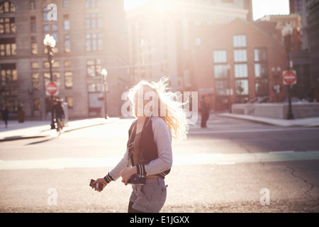 Young woman walking down street à Boston, faisant appareil photo et téléphone intelligent Banque D'Images