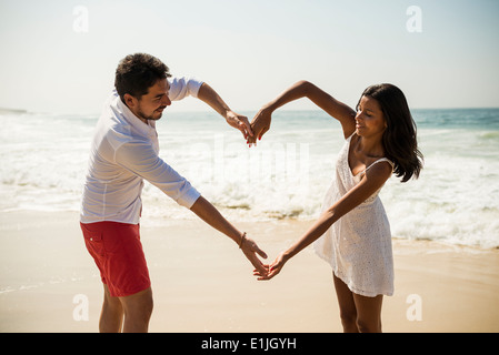 Couple forme de coeur avec des bras on Arpoador beach, Rio de Janeiro, Brésil Banque D'Images