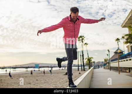 Jeune homme en équilibre sur mur, Long Beach, Californie, USA Banque D'Images