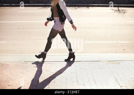 Jeune femme avec caméra walking down street Banque D'Images