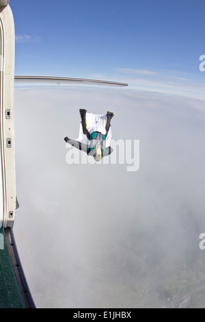 Mid adult man volant au-dessus des nuages en wingsuit Banque D'Images