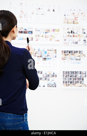 Young woman looking at photographs in studio Banque D'Images