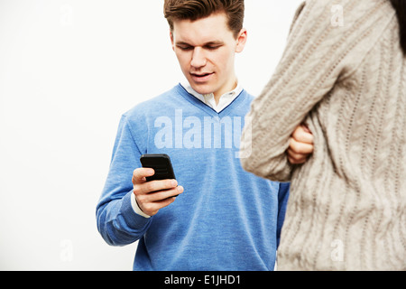 Young man using smartphone, femme en premier plan Banque D'Images